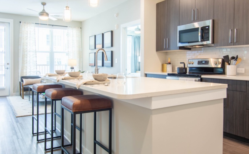 Large open kitchen and living space with wood-style floors and quartz counters at Element Galleria Apartments